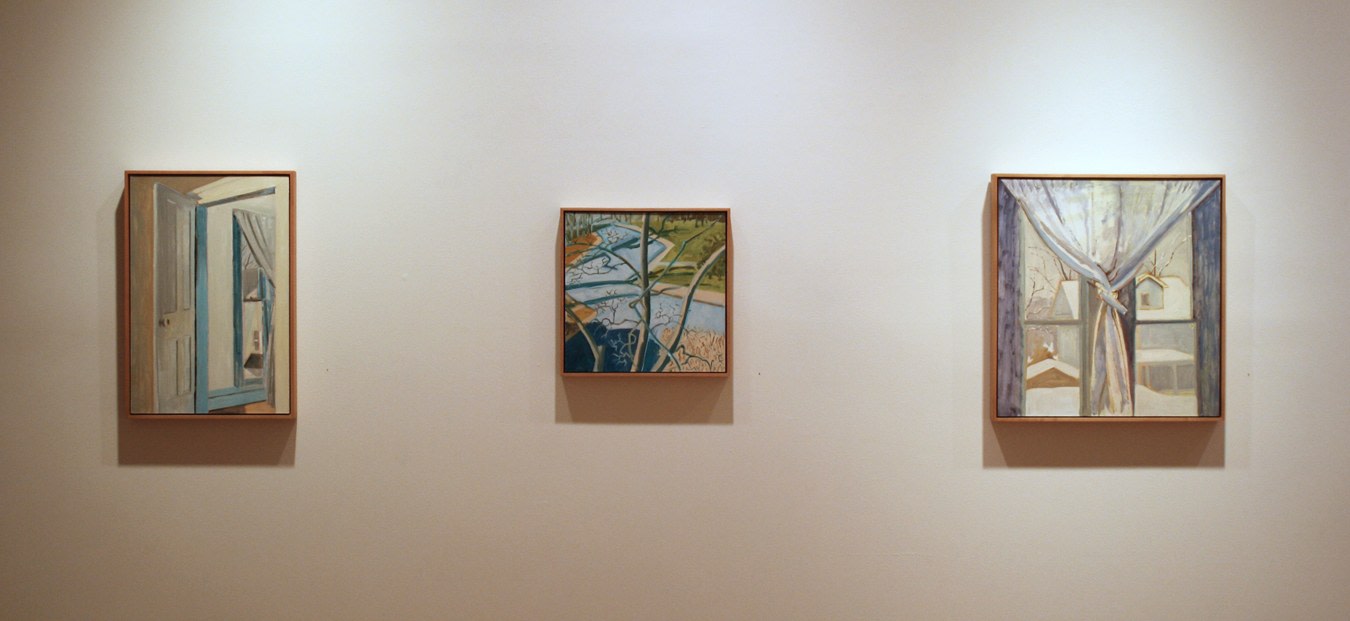 Photograph showing a view of an exhibition, with three small framed paintings hanging on a white wall