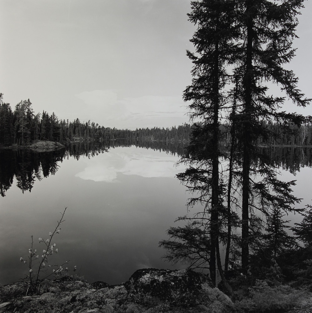 Black and white photograph of a body of water surrounded by trees