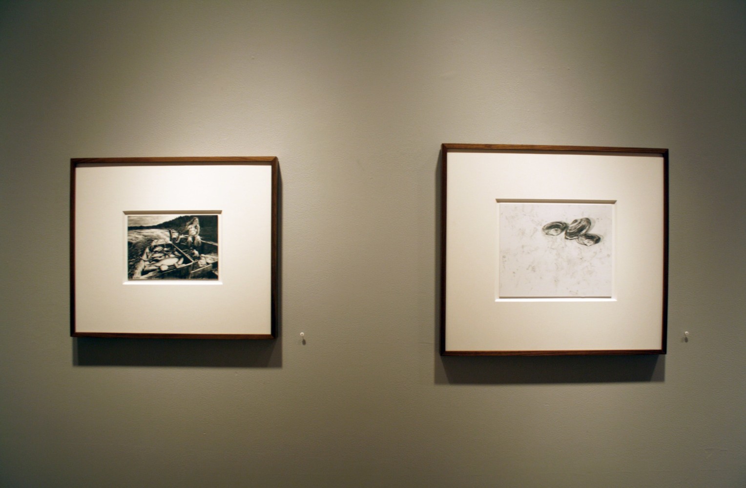 Photograph showing a view of an exhibition, with two small framed drawings hanging on a grey wall