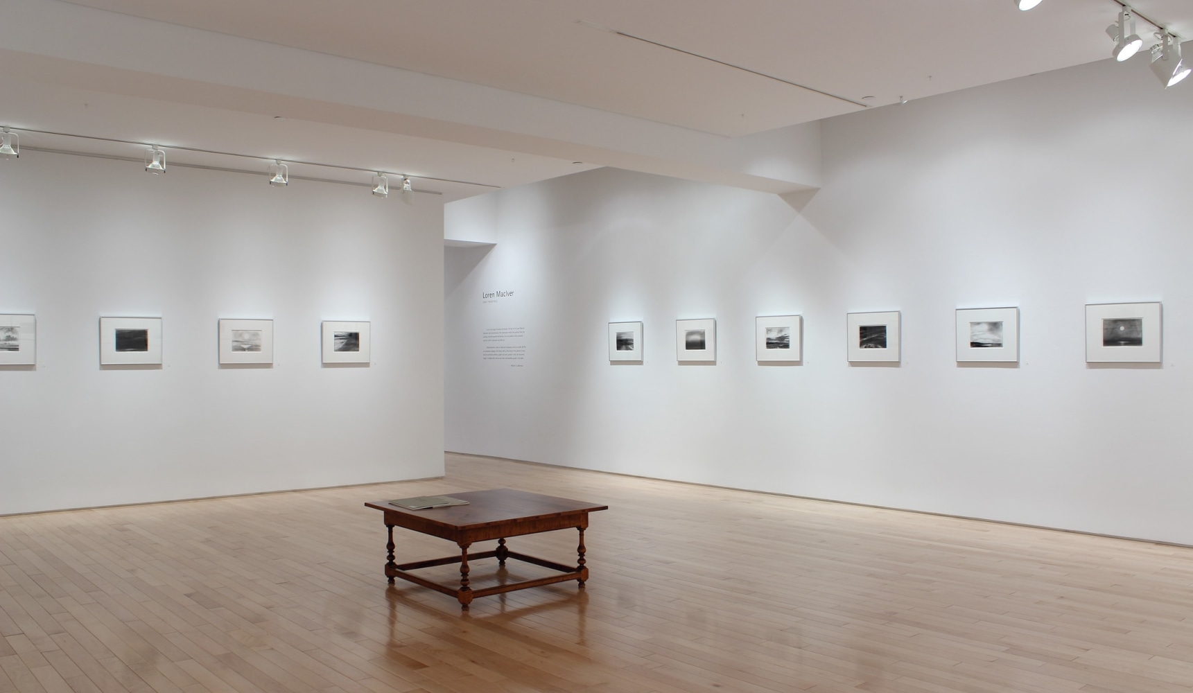 Photograph of showing a corner view of an exhibition space, with ten drawings hanging on white walls.