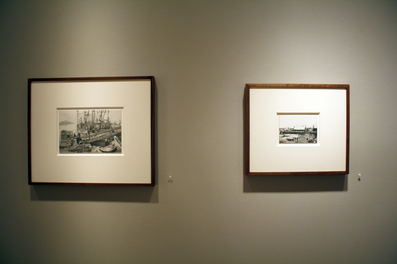 Photograph showing a view of an exhibition, with two small framed drawings hanging on a grey wall