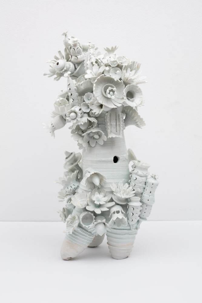 Picture of a white porcelain sculpture with sculpted flowers coming out the top and sides