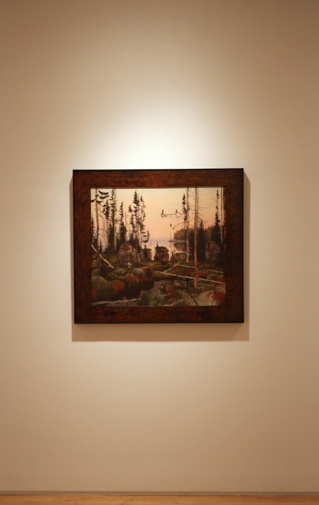 Photograph showing a view of an exhibition, with one framed painting hanging on a white wall