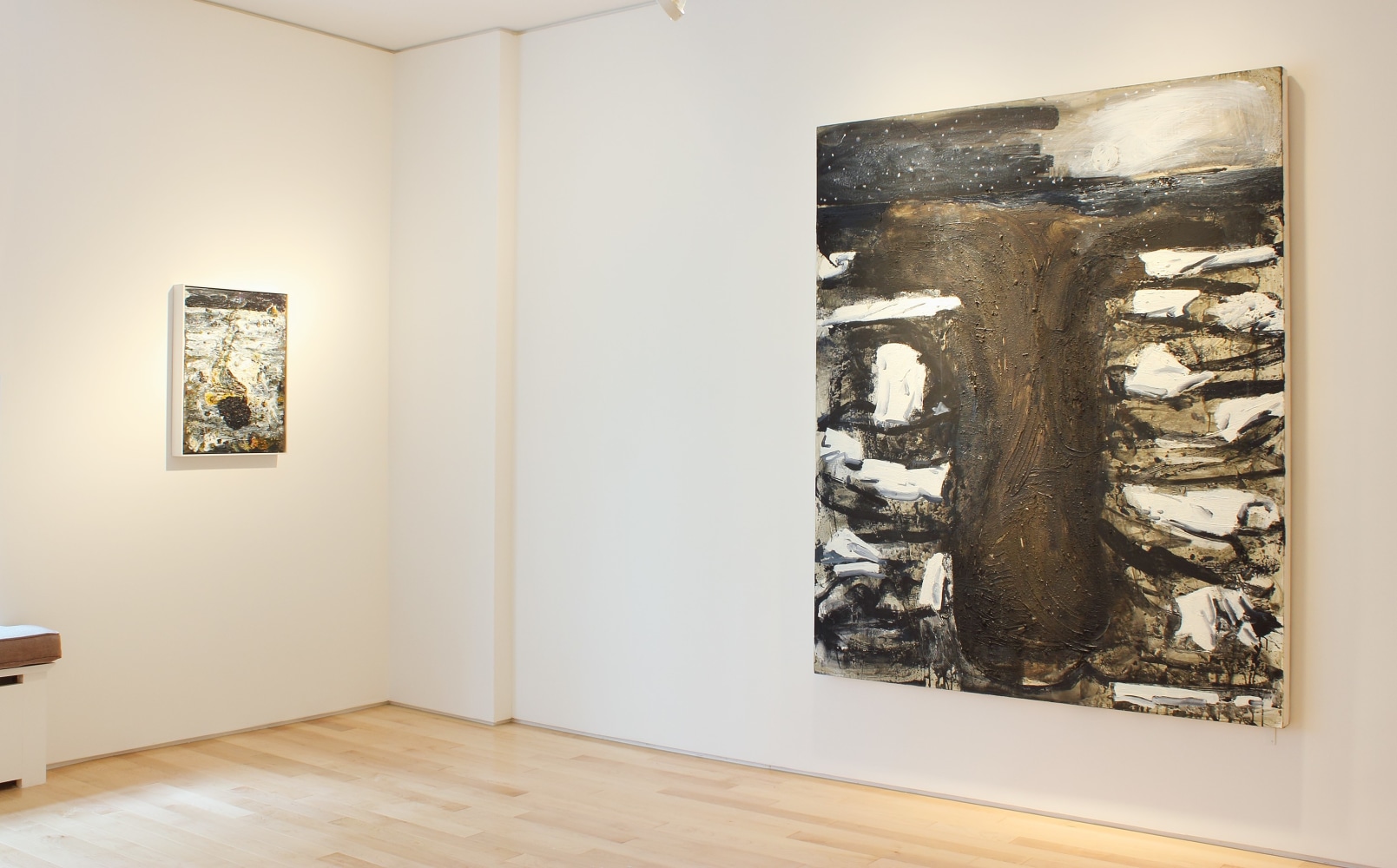 Photograph showing a corner view of an exhibition space, with one large painting and one small painting hanging on white walls