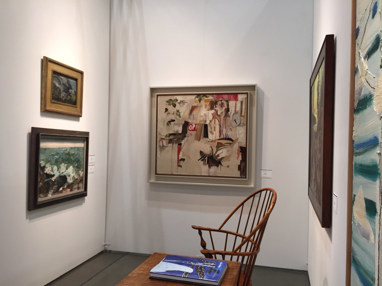 Photograph showing a view of an exhibition space, with four paintings of various sizes hanging on white walls