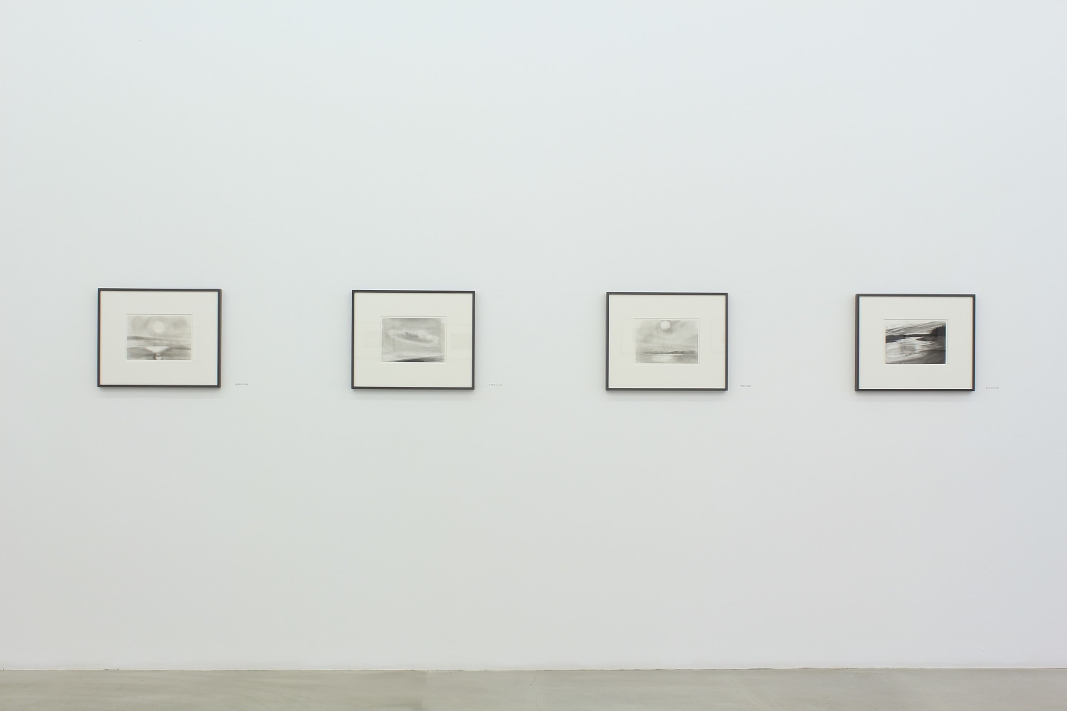 Photograph of four framed drawings on a white wall