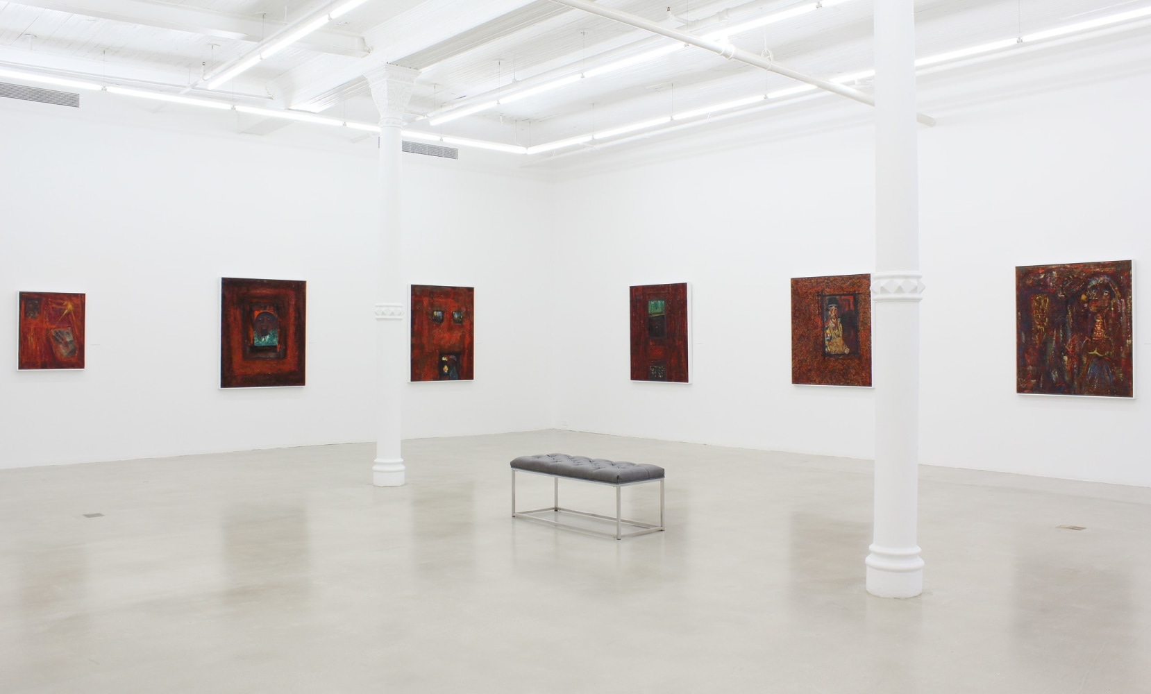 Photograph showing a corner view of an exhibition space, with six paintings hanging on white walls