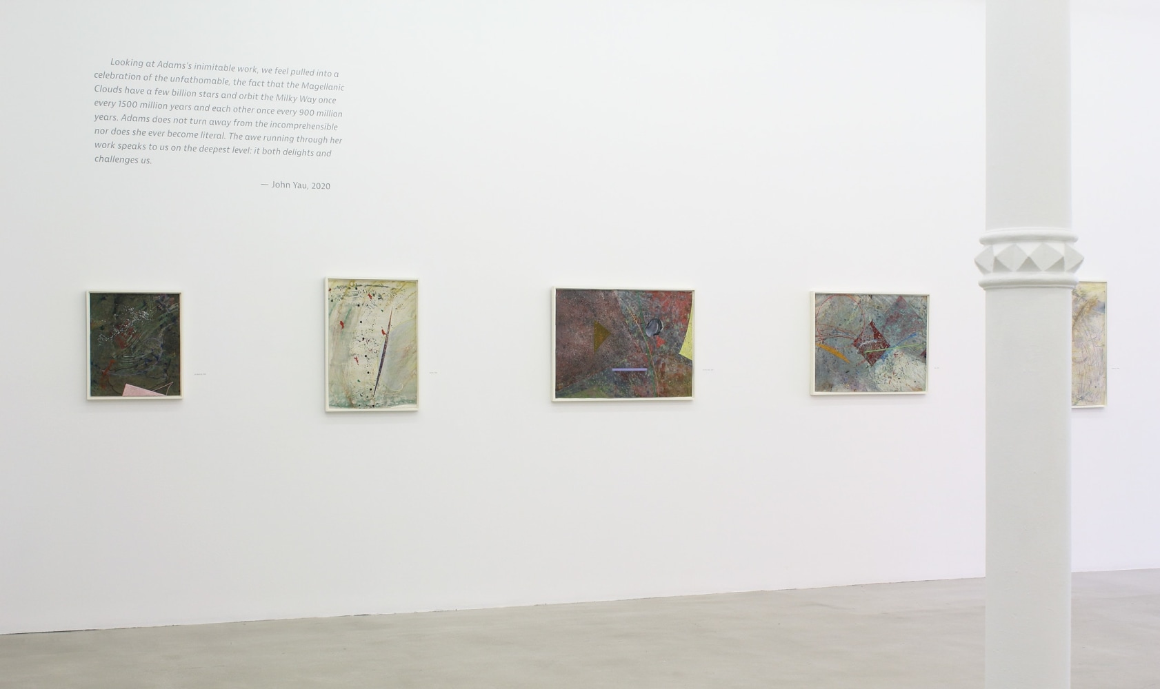 Photograph showing a view of an exhibition space, with five paintings hanging on a white wall