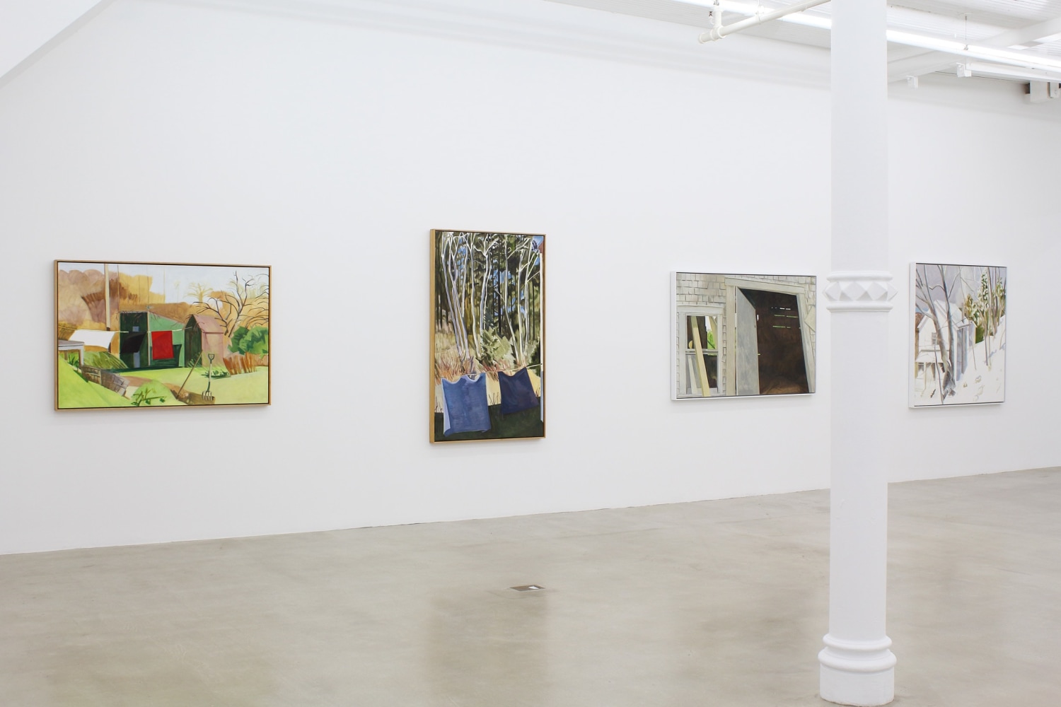 Photograph showing a view of an exhibition space, with four paintings hanging on a white wall