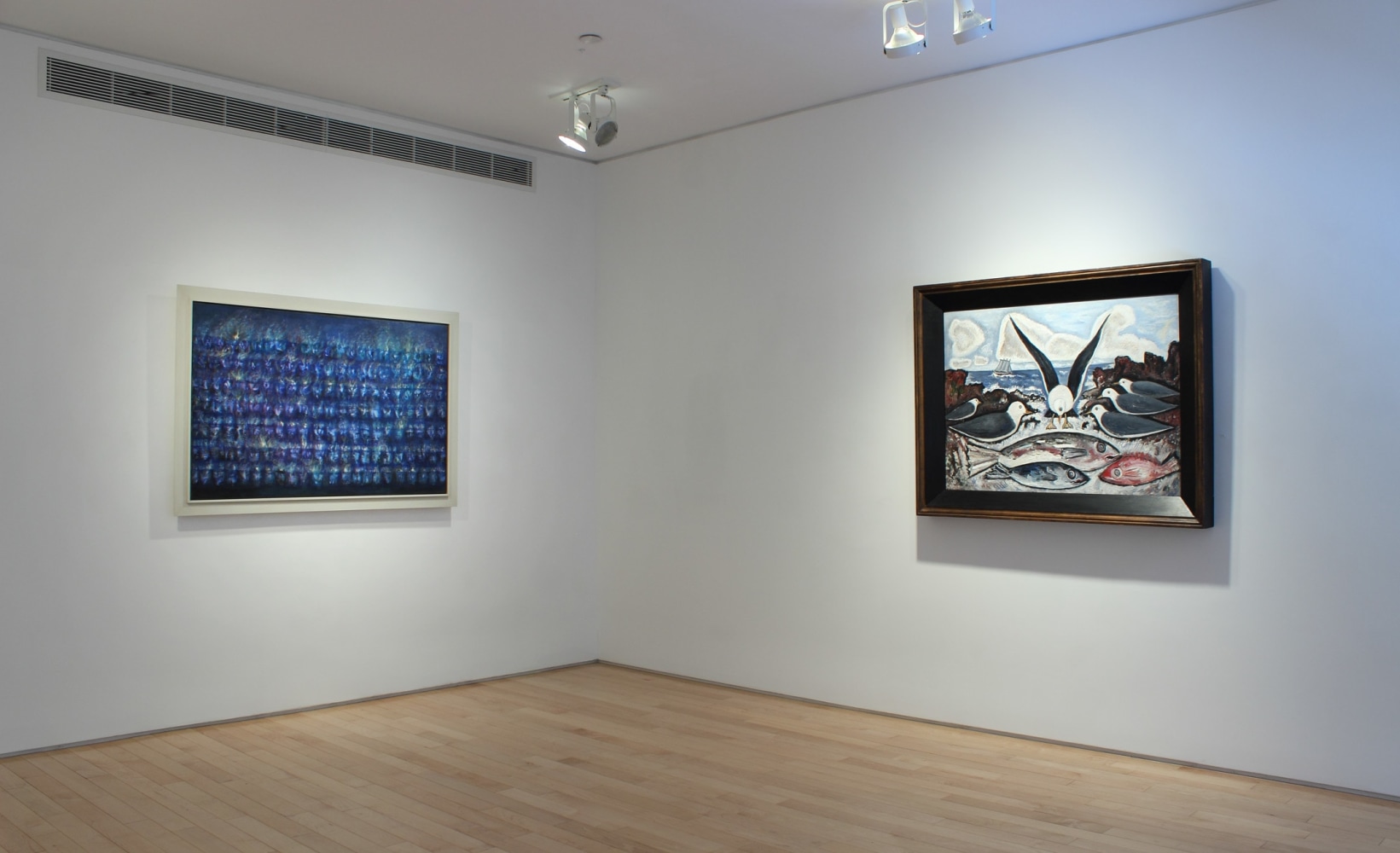 Photograph showing a corner view of an exhibition space, with two paintings hanging on white walls