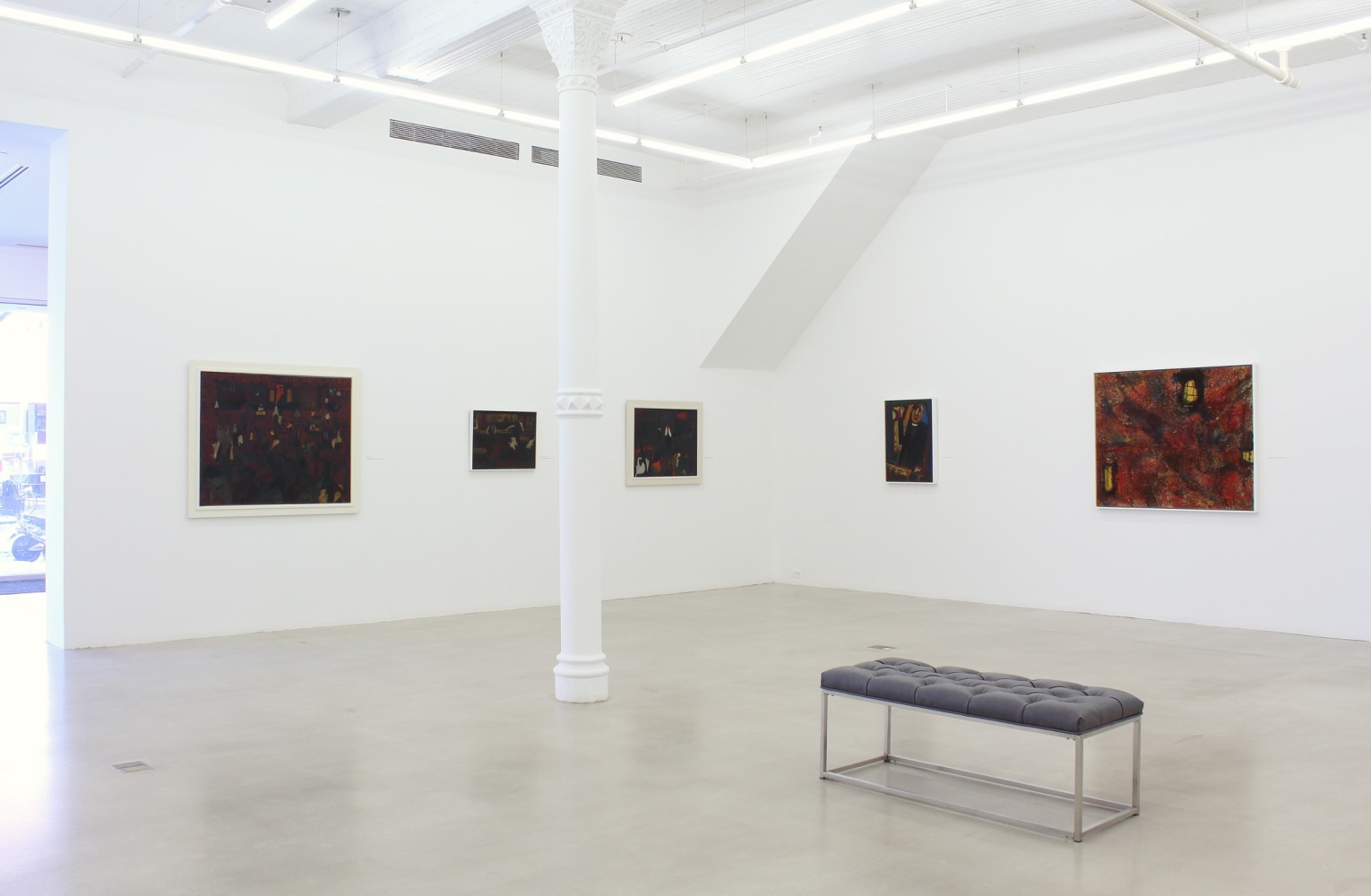 Photograph showing a corner view of an exhibition space, with five paintings hung on white walls