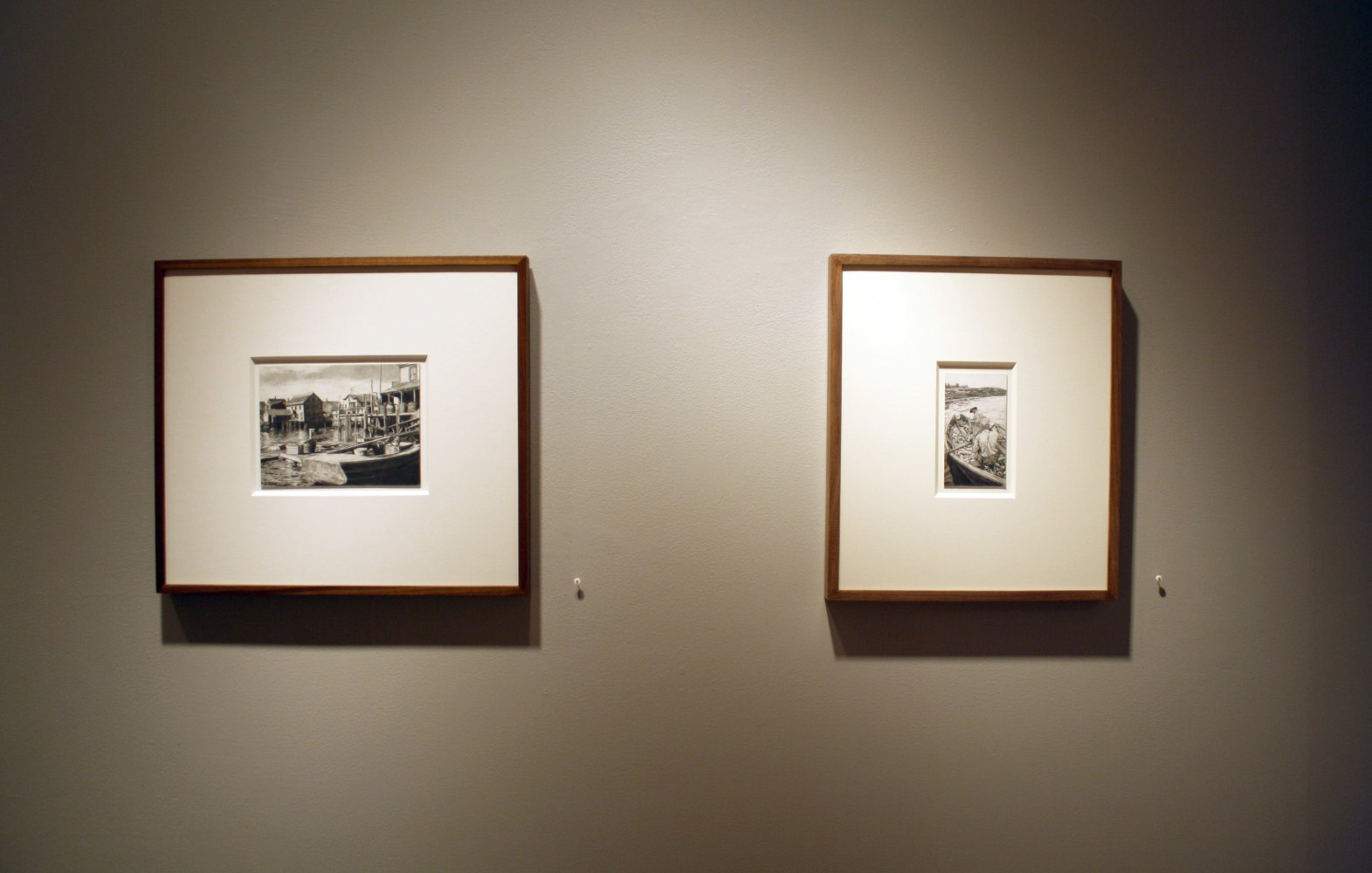 Photograph showing a view of an exhibition, with two small framed drawings hanging on a grey wall