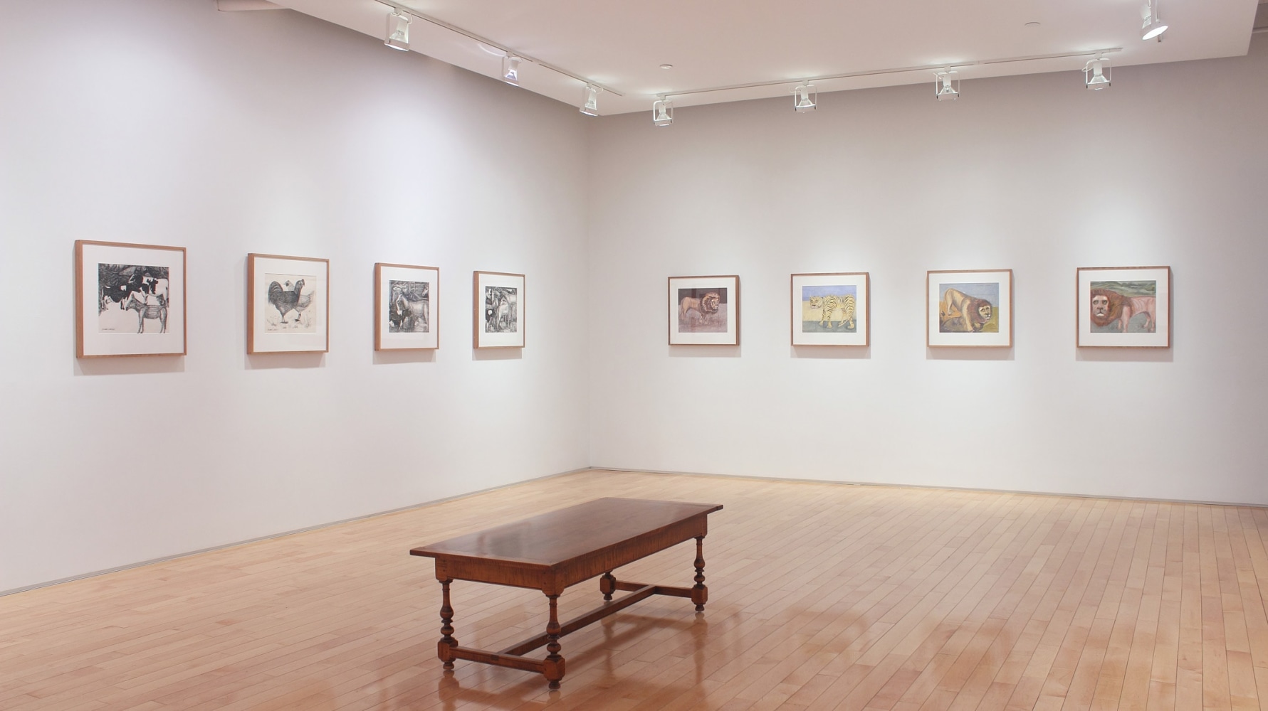 Photograph showing a corner view of an exhibition space with eight framed paintings hanging on a white wall