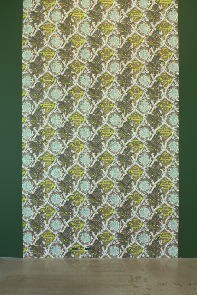 Photograph of a long strip of wallpaper made up of criss-crossing branches and lichen and ferns on a brick wall