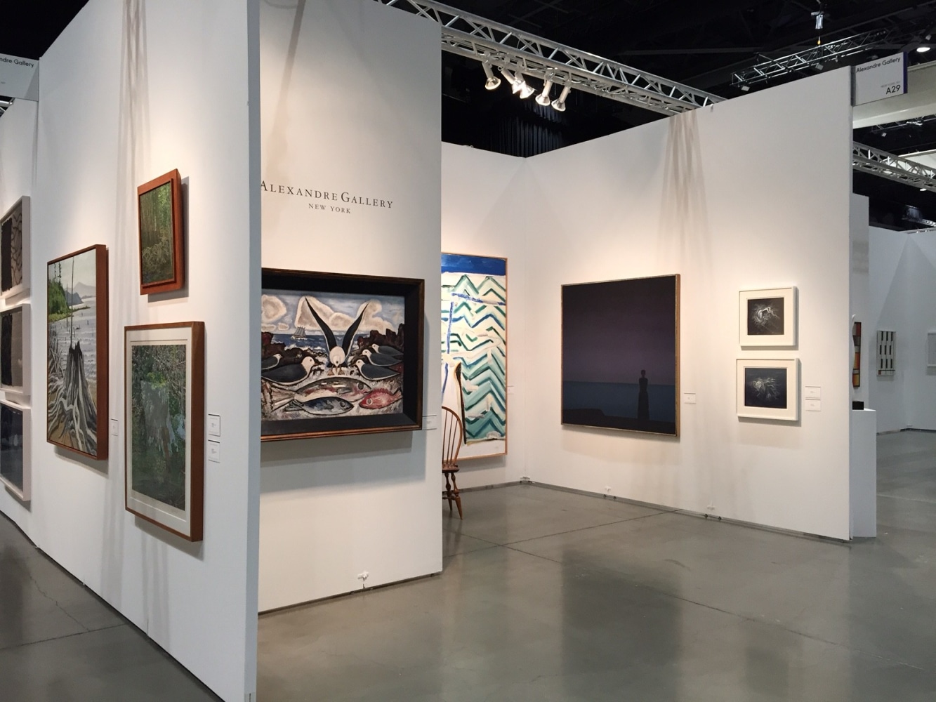Photograph showing a view of an exhibition space, with eight paintings of various sizes hanging on white walls