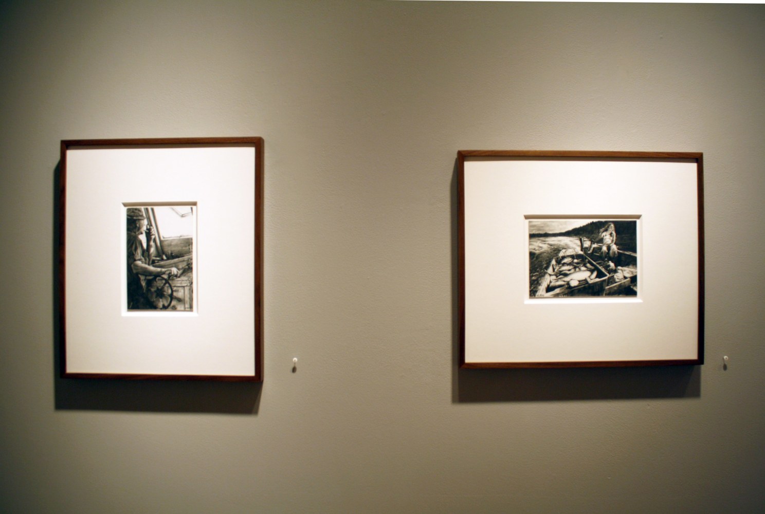 Photograph showing a view of an exhibition, with two small framed drawings hanging on a grey wall