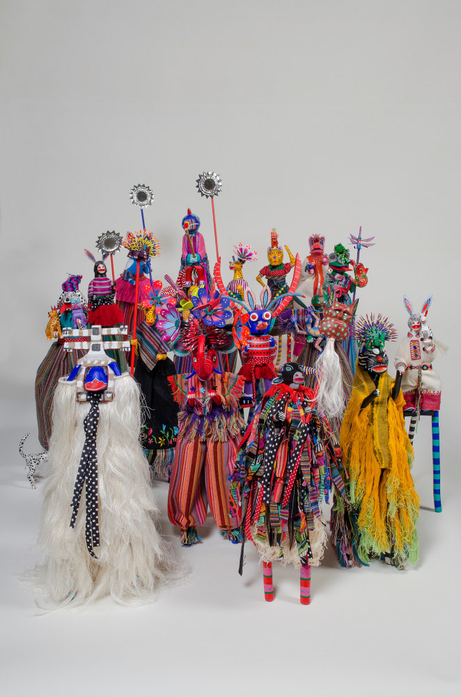 A culster of small, colorful figures on stilts against a gray backdrop