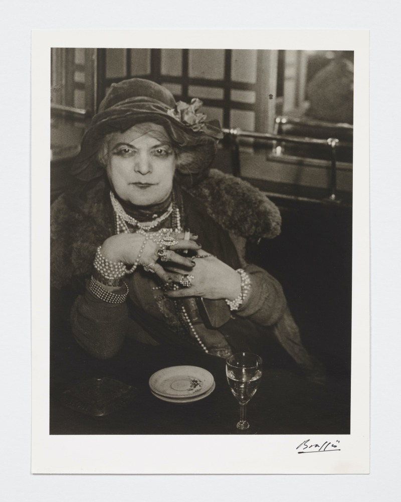 Black and white photographic portrait of woman in pearls and velvet hat.