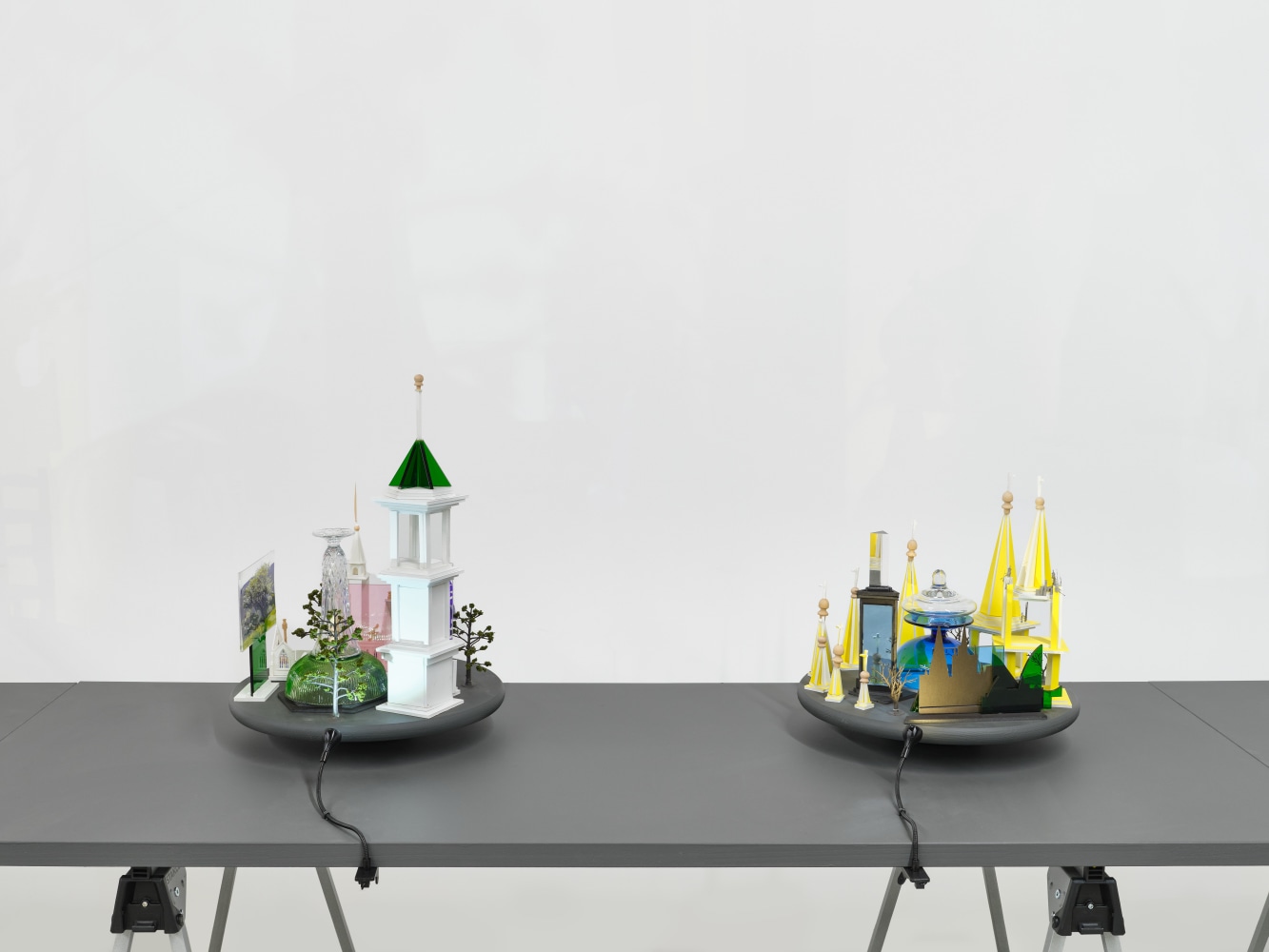 A series of assemblage sculptures comprised of upside down crystal vases, miniature street lamps, photographs printed on plexiglass and steeples made from styrene atop rotating platforms.