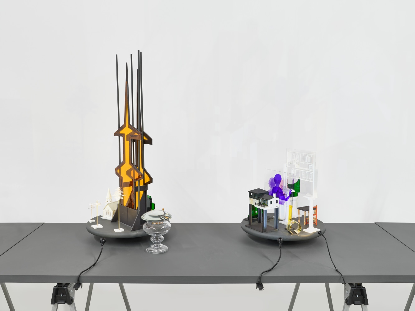 A series of assemblage sculptures comprised of upside down crystal vases, miniature street lamps, photographs printed on plexiglass and steeples made from styrene atop rotating platforms.