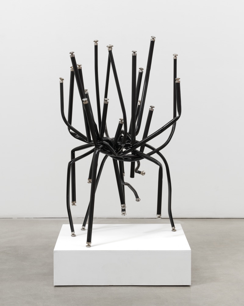 A free standing sculpture by Josh Callaghan of black metal chair legs entangled and extending skyward.