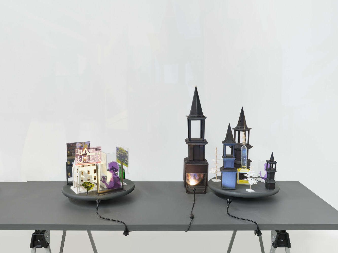 A series of assemblage sculptures comprised of upside down crystal vases, miniature street lamps, photographs printed on plexiglass and steeples made from styrene atop rotating platforms.