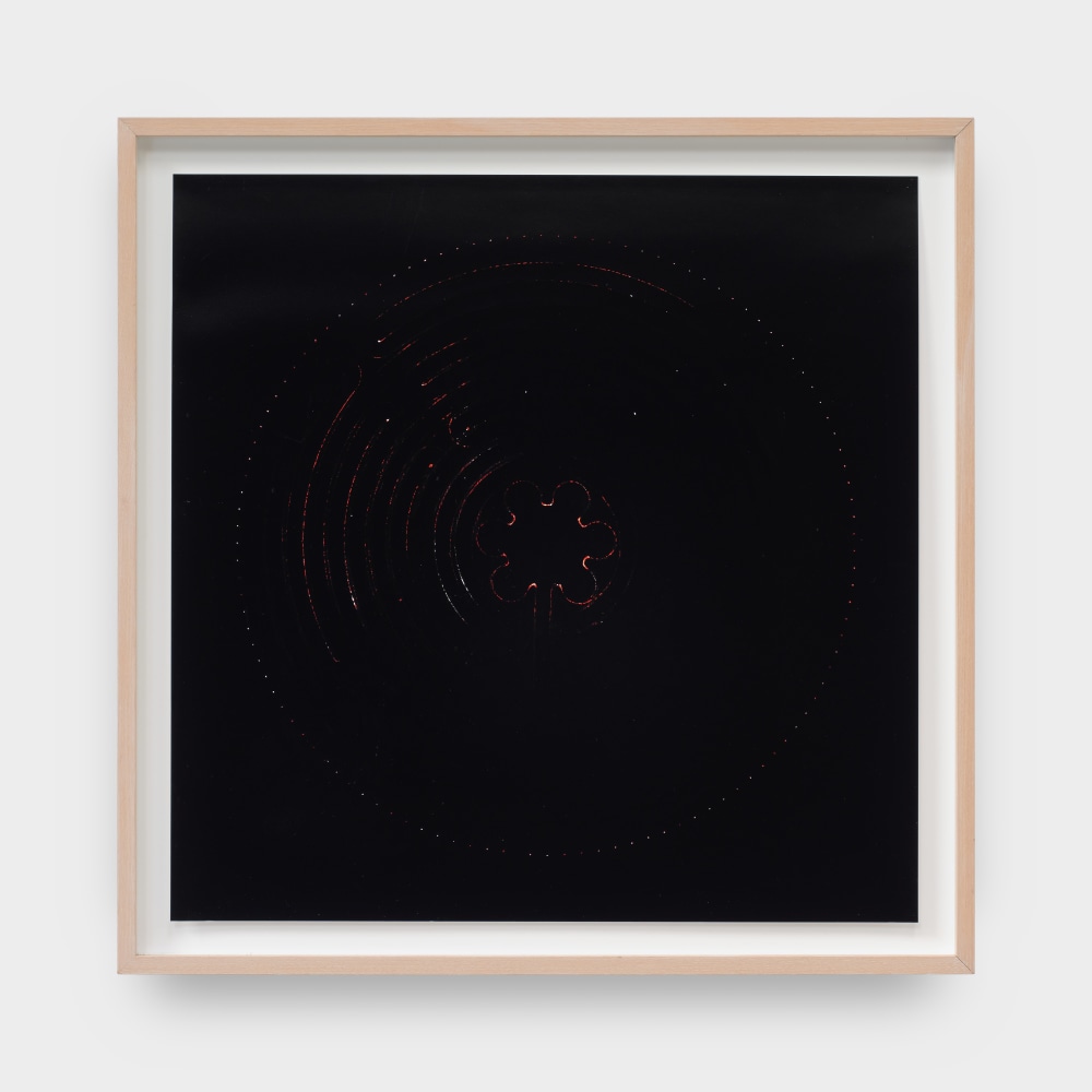 A framed artwork by Laura Howard Parker of black pigment with rounded and floral shapes scratched into the paper.