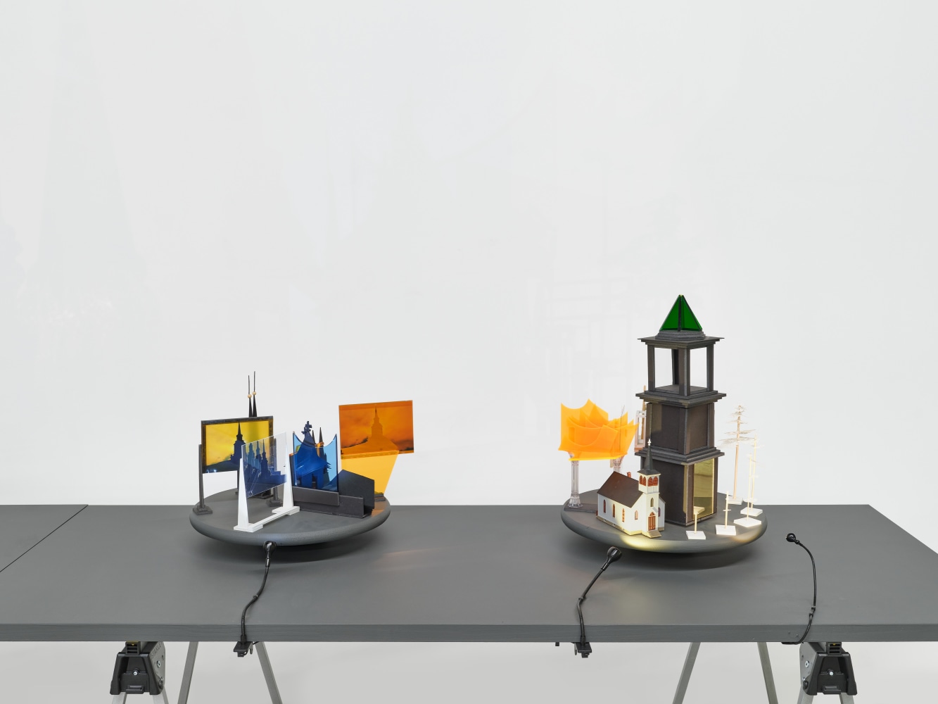 A series of assemblage sculptures comprised of upside down crystal vases, miniature street lamps, photographs printed on plexiglass and steeples made from styrene atop rotating platforms.