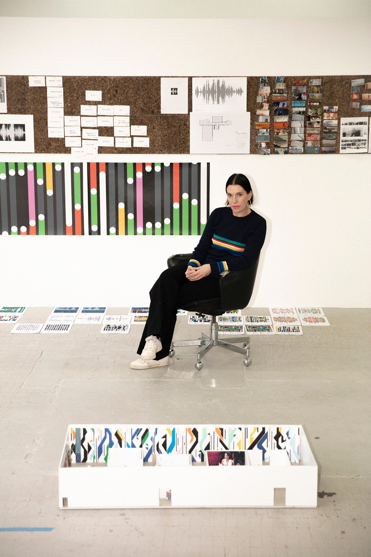 A portrait of Sarah Morris sitting in her studio