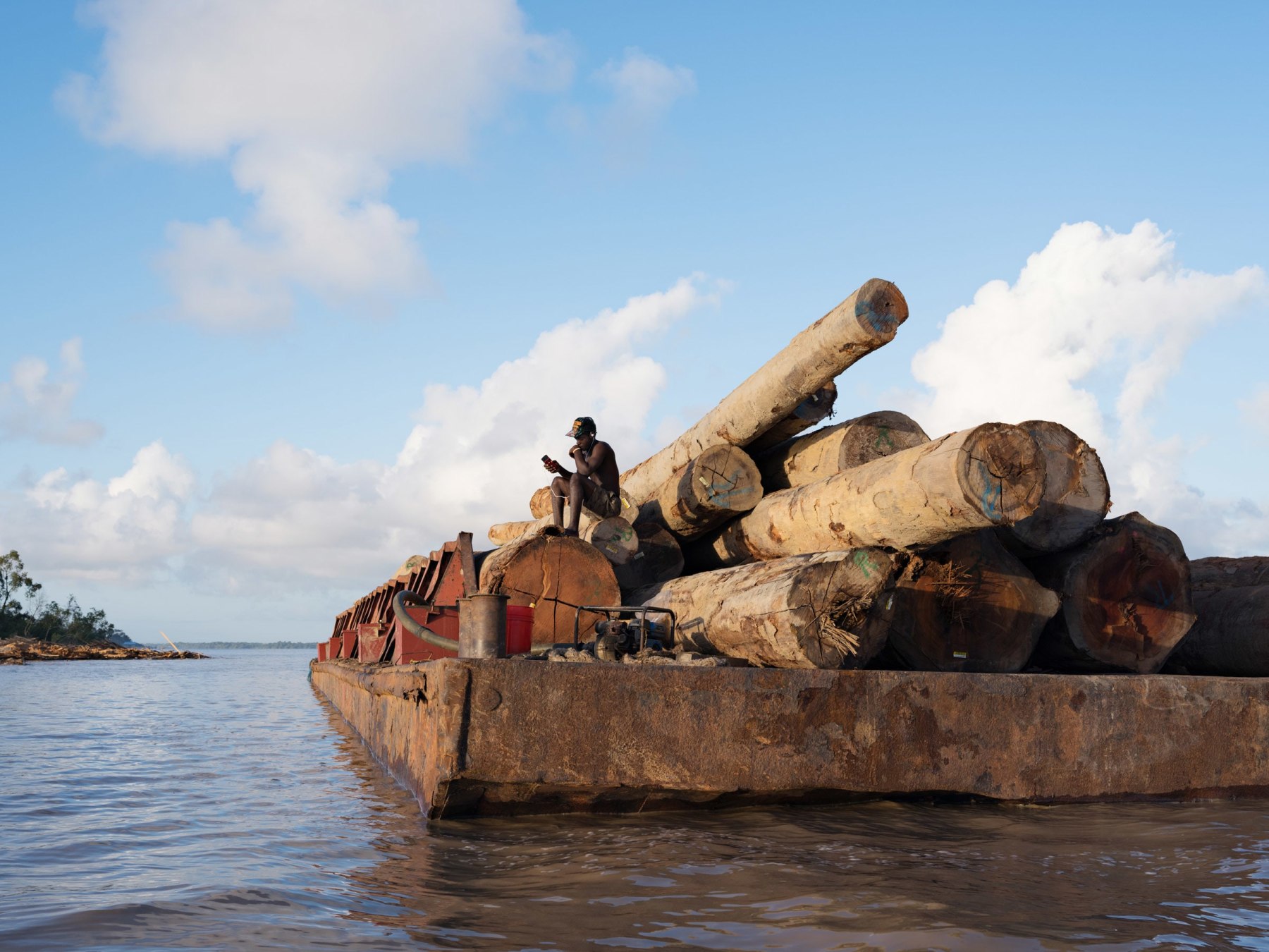 LUCAS FOGLIAKurt Guarding Logs for Export to China, Essequibo River, Guyana, 2016, Pigment Print34 x 44 inchesEdition of 8