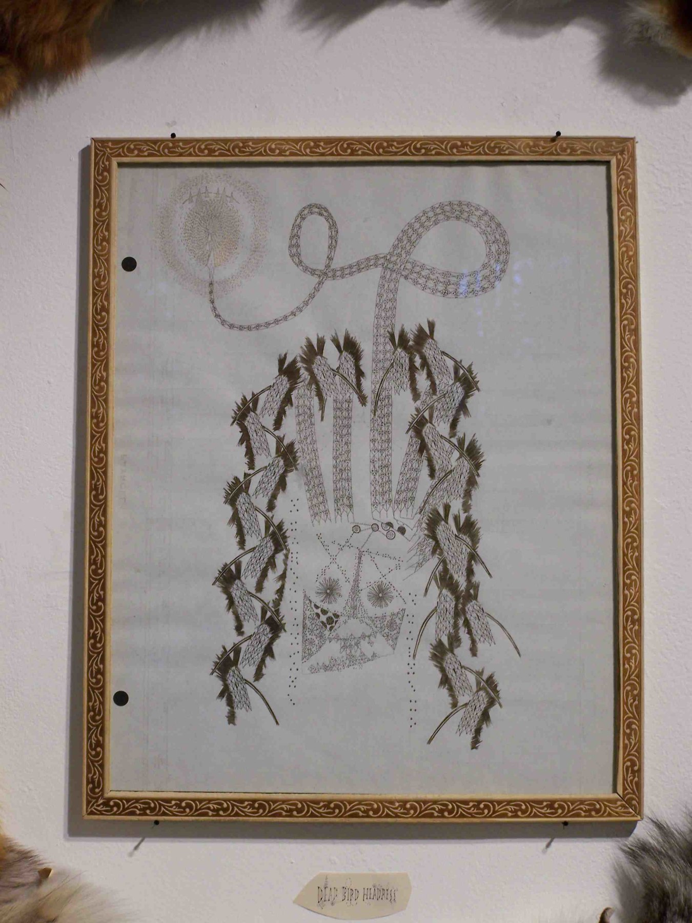 Framed scorpion drawing surrounded by fur on gallery wall