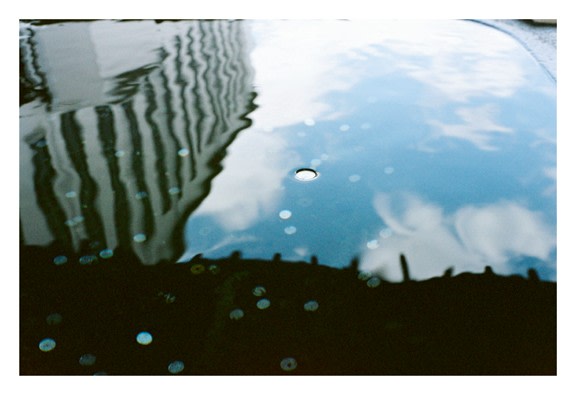 photo of tall building reflected in water puddle