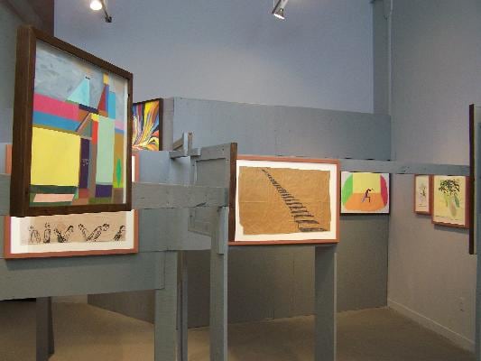Installation view of framed pieces on wooden constructions