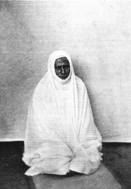 Black and white postcard of woman kneeling on matt