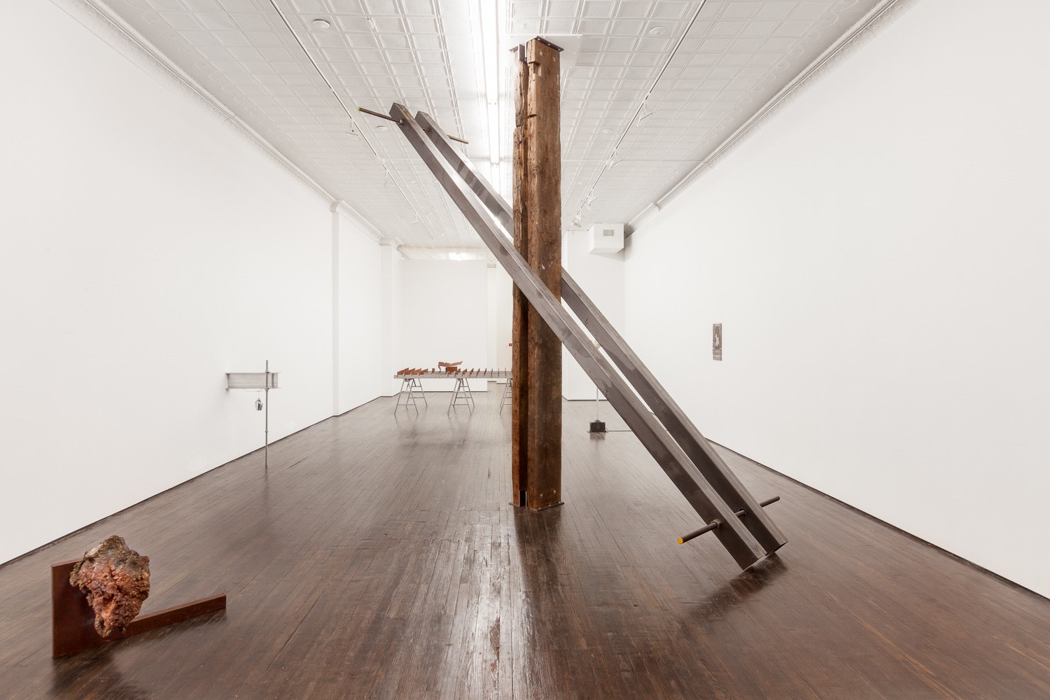 wooden and metal piling sculpture in gallery