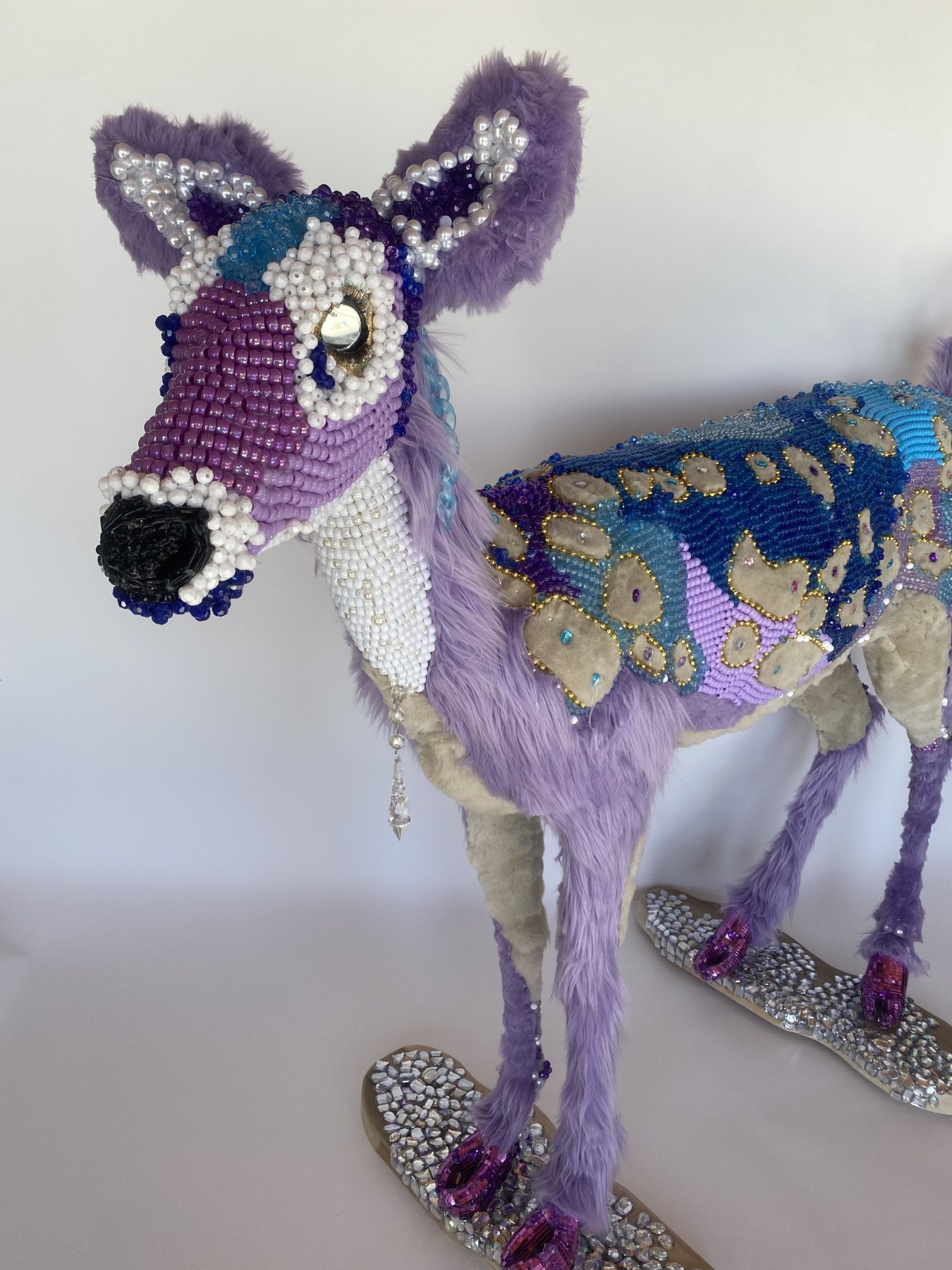 Purple and blue beaded deer sculpture featuring purple faux fur, mirror eyes, and glitter eyelashes.