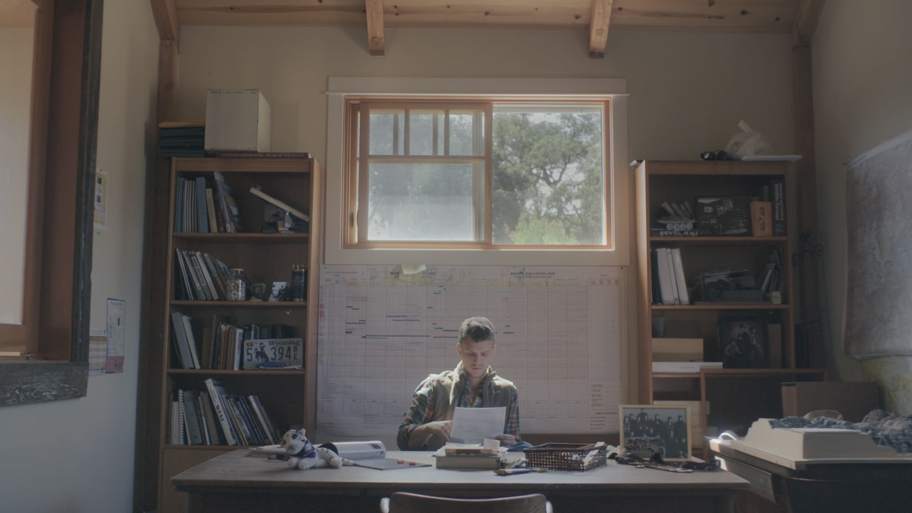 Man reading a paper in a room with 2 bookshelves