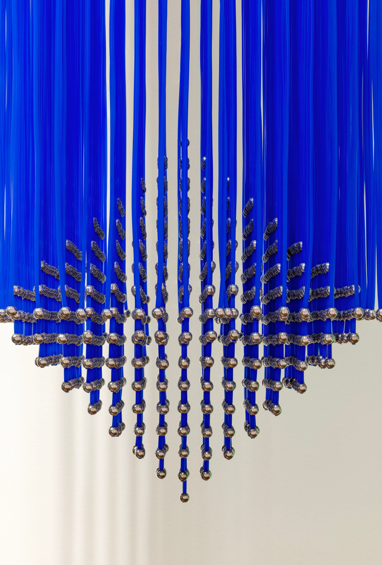 Hanging sculpture with metal balls attached to blue strips of plastic