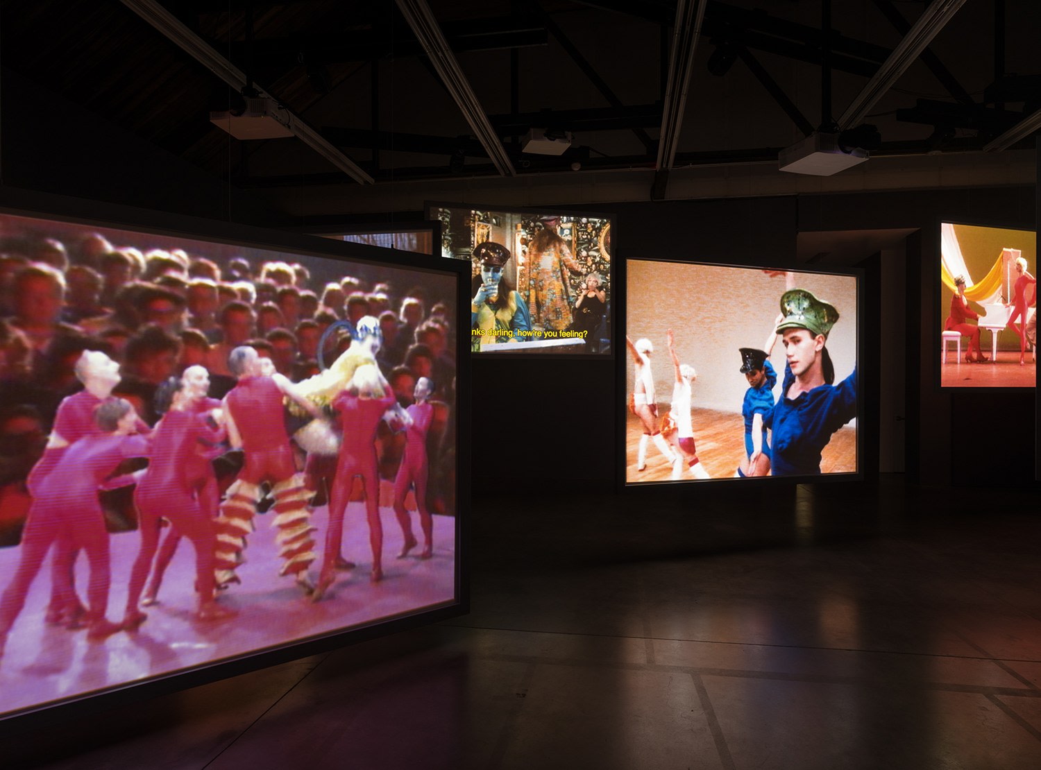 4 video screens in an art gallery showing dance routines