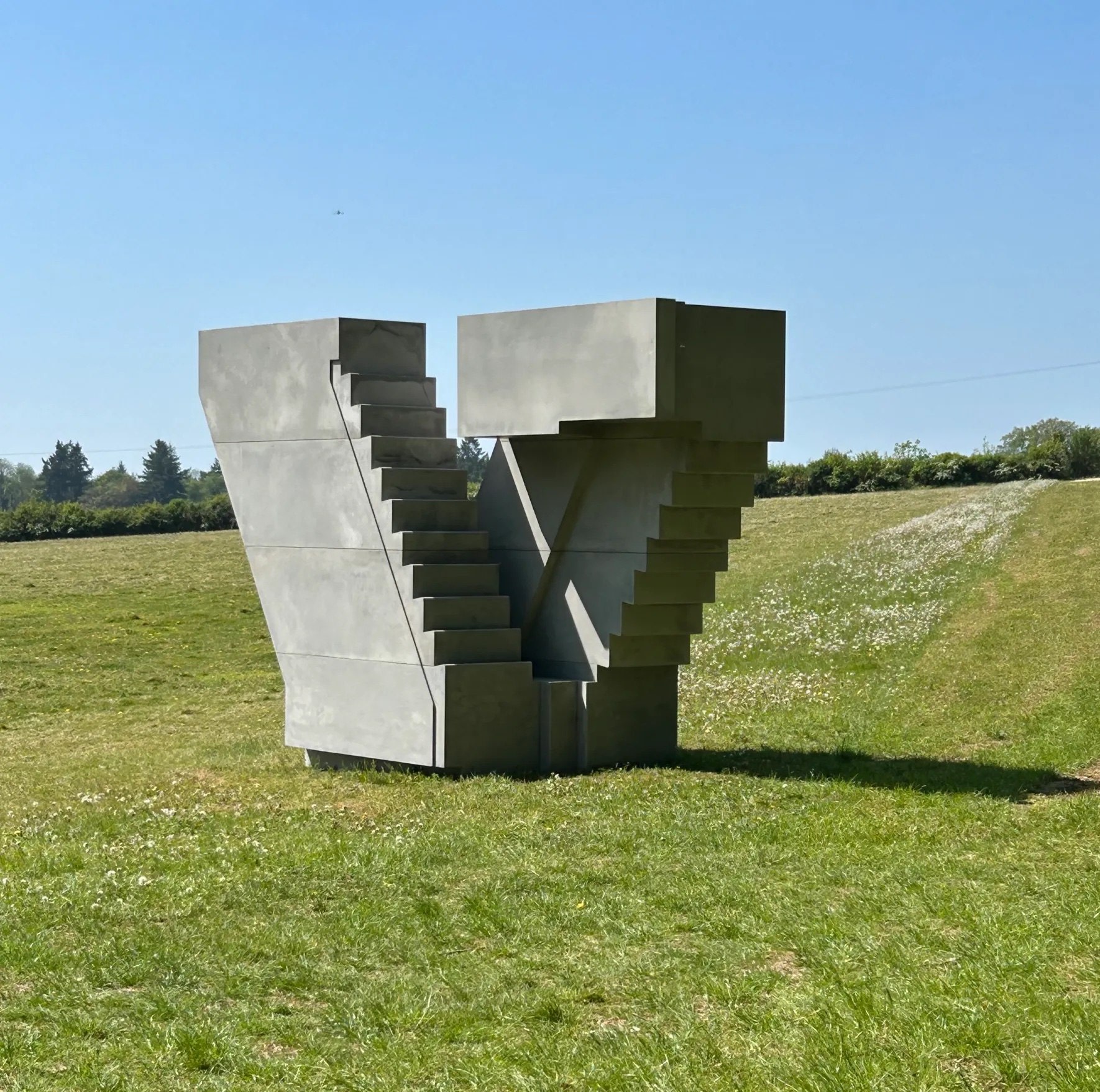 Concrete sculpture of stairs on a grassy field