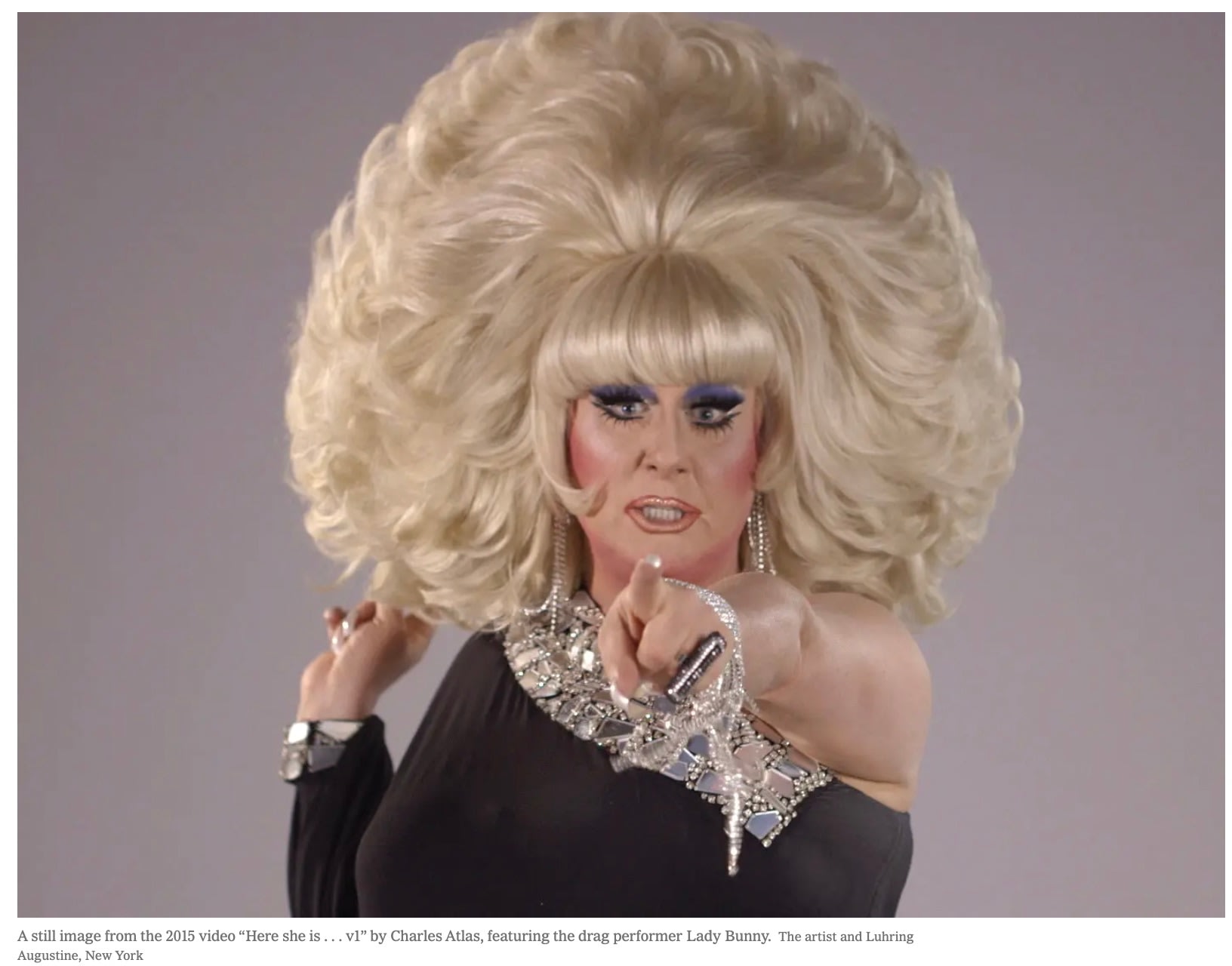 The drag performer Lady Bunny pointing at the camera, wearing a large blonde wig and black dress