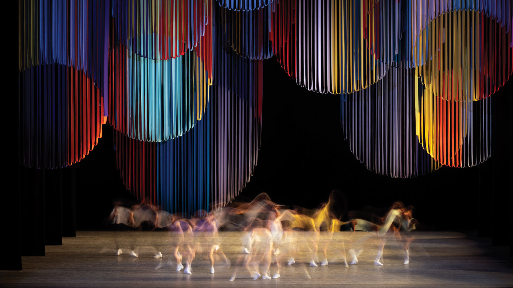 Dancers performing on a stage with hanging circular ribbons as a backdrop