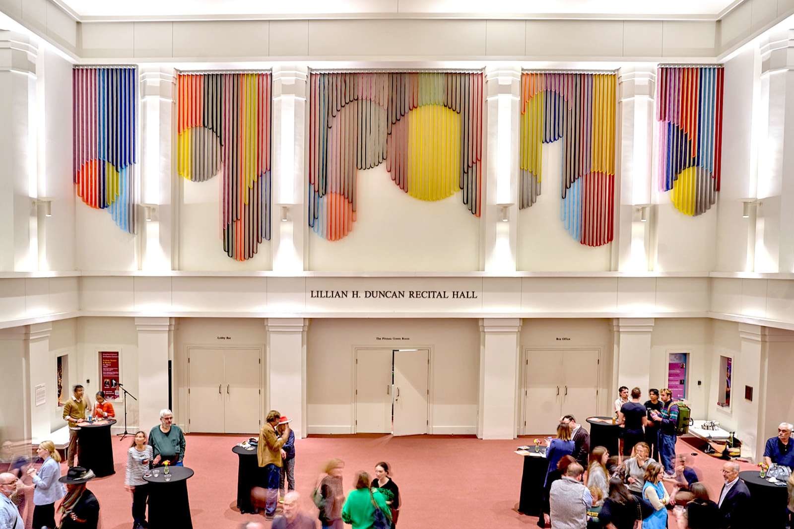 Art installation of multiple colored strips forming geometric shapes in a lobby of a recital hall