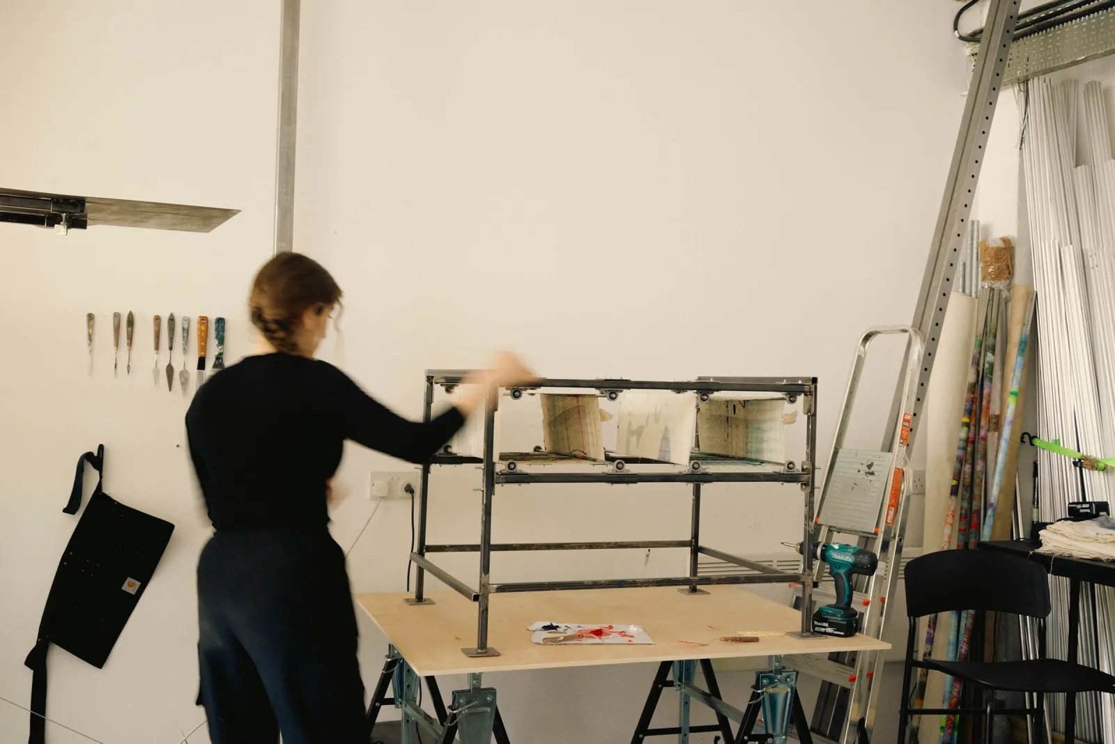 A female artist in her studio creating a painting using a cube-like structure