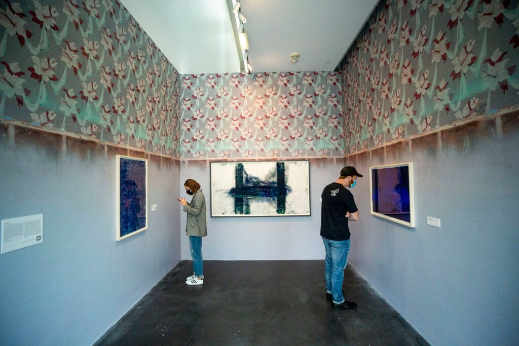 Installation of museum show: 3 works on paper under patterned wallpaper