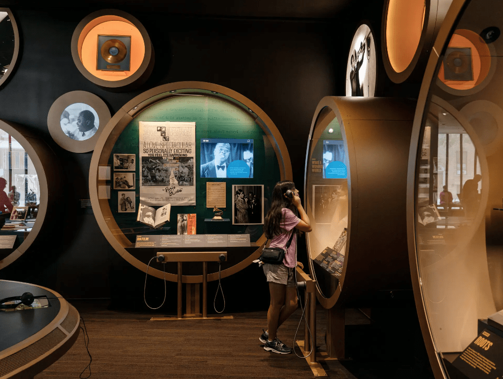 installation shot of Louis Armstrong exhibition with photographs, records, and listening stations