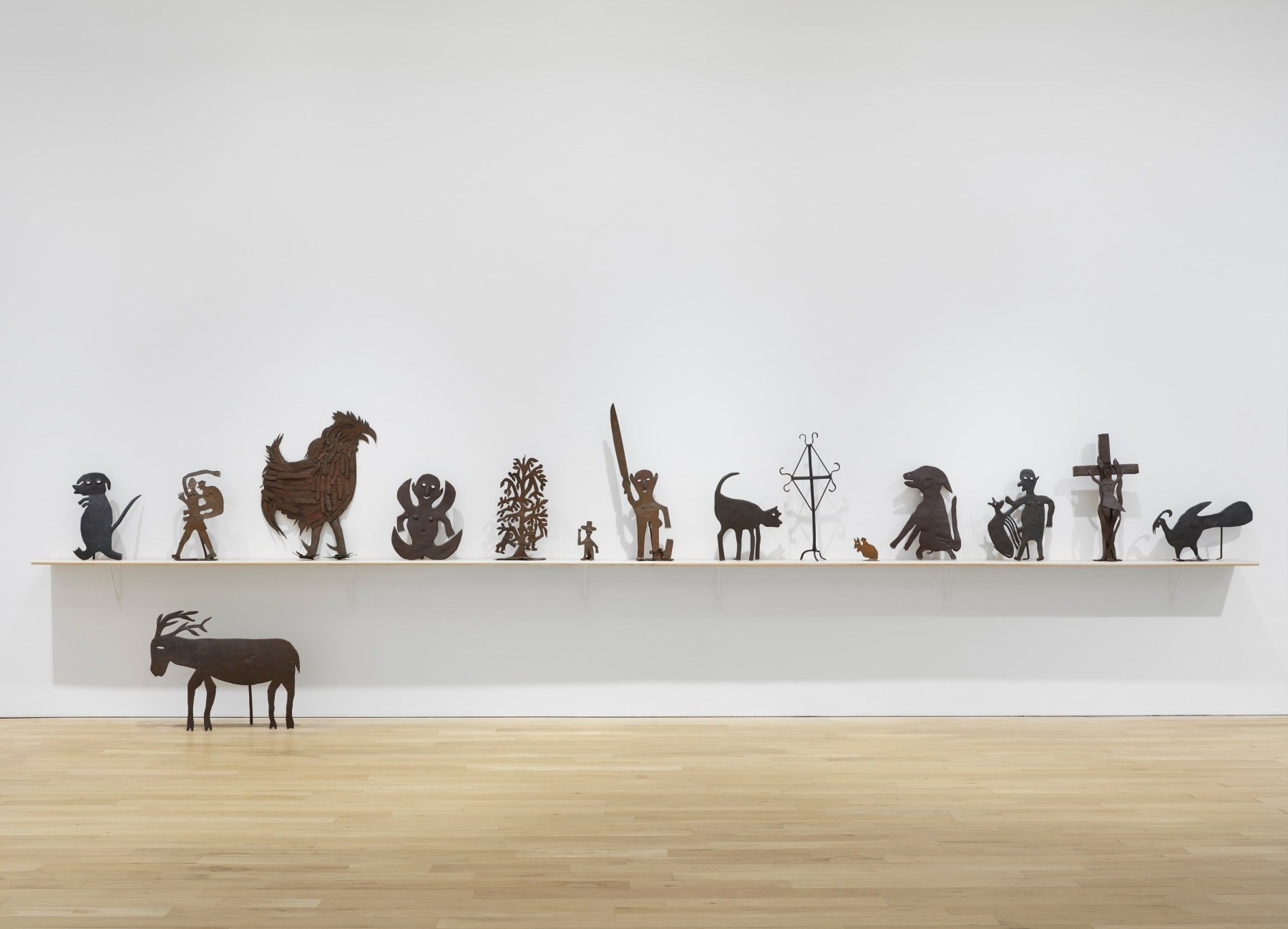 A set of metal sculptures depicting animals and human figures installed in an art gallery