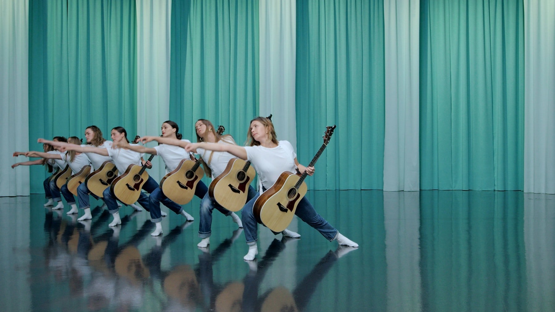 8 female dancers holding guitars