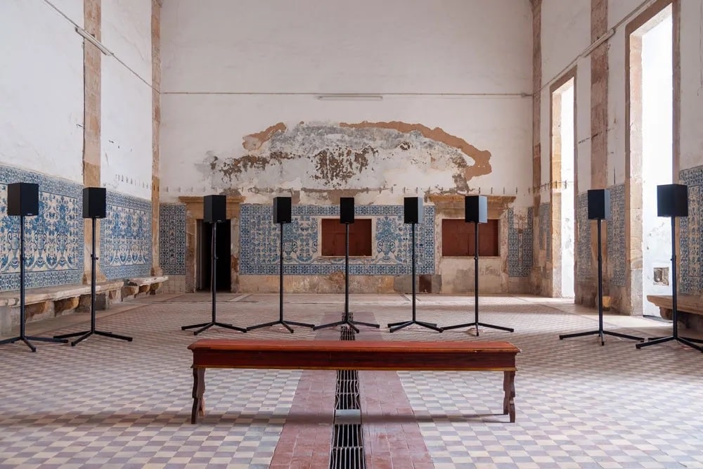 Sound installation with multiple speakers and a bench in a old church