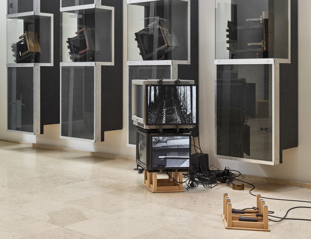 Art installation with television sets and glass and metal vitrines